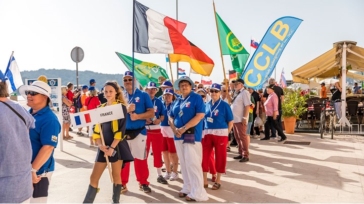 Eine Gruppe von Menschen hält verschiedene Nationalflaggen bei einer Veranstaltung im Freien