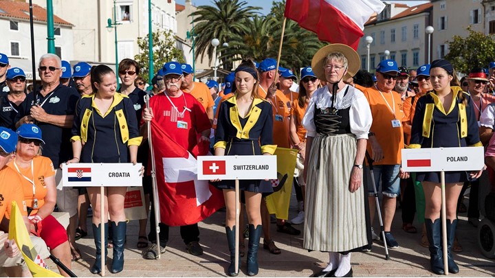 Skupina ljudi drži razne nacionalne zastave na događaju na otvorenom