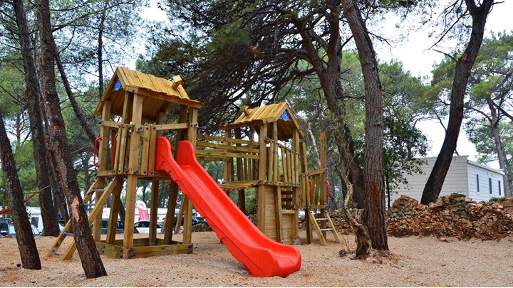 Wooden playground with a red slide among trees