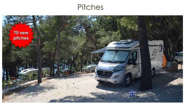 Un camper parcheggiato in un'area campeggio ombreggiata con alberi intorno