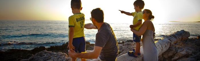 Eine Familie beobachtet den Sonnenuntergang am Meer