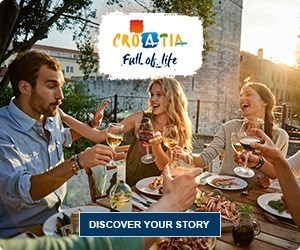 Ljudje uživajo v obroku in pijači v restavraciji na prostem s turističnim logotipom Hrvaške