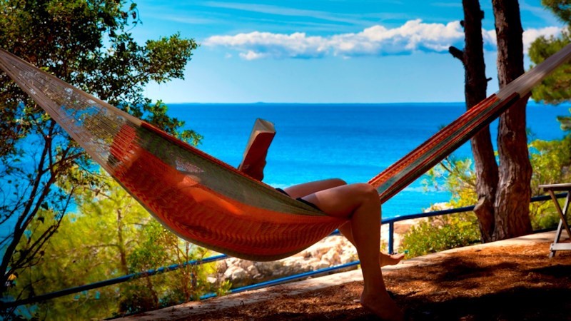 Person relaxing in a hammock by the sea